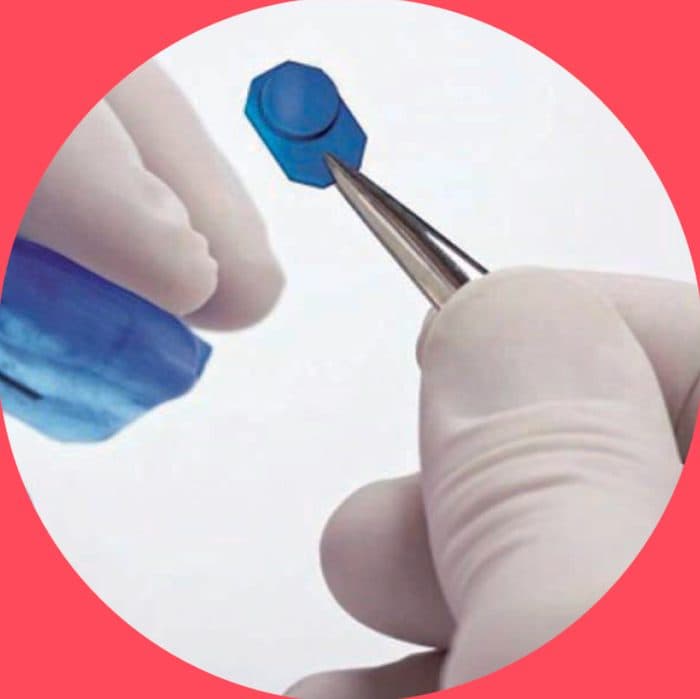 Gloved hand holding a small blue theramon microsensor with tweezers