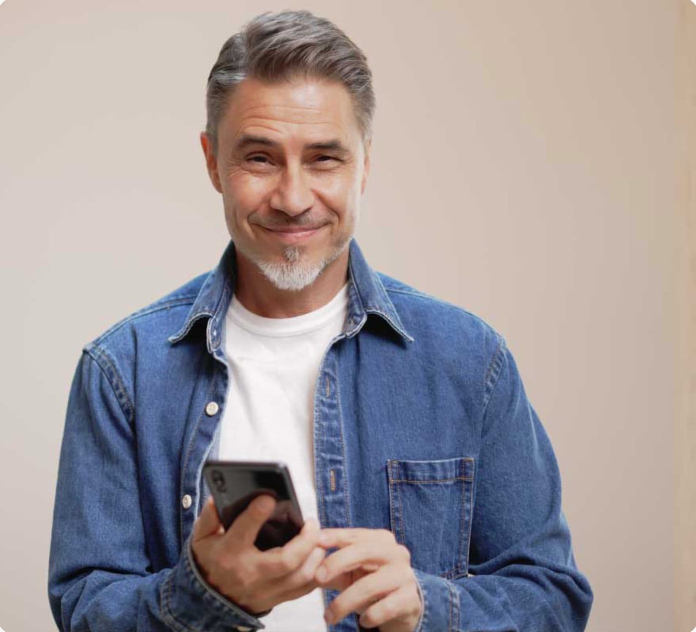 Smiling man in a denim shirt holding a phone