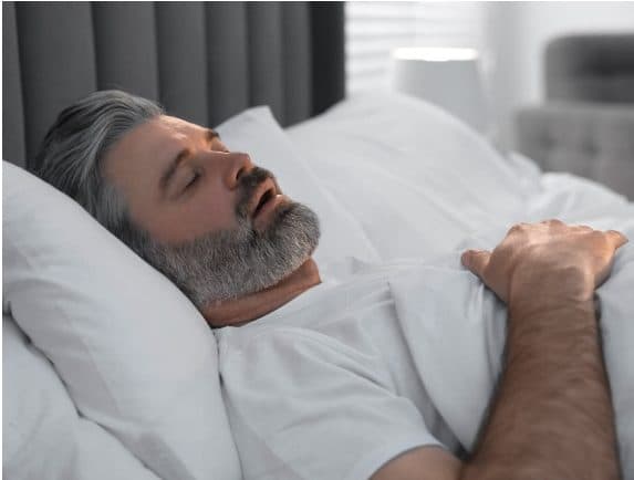 Man asleep in bed with his mouth open