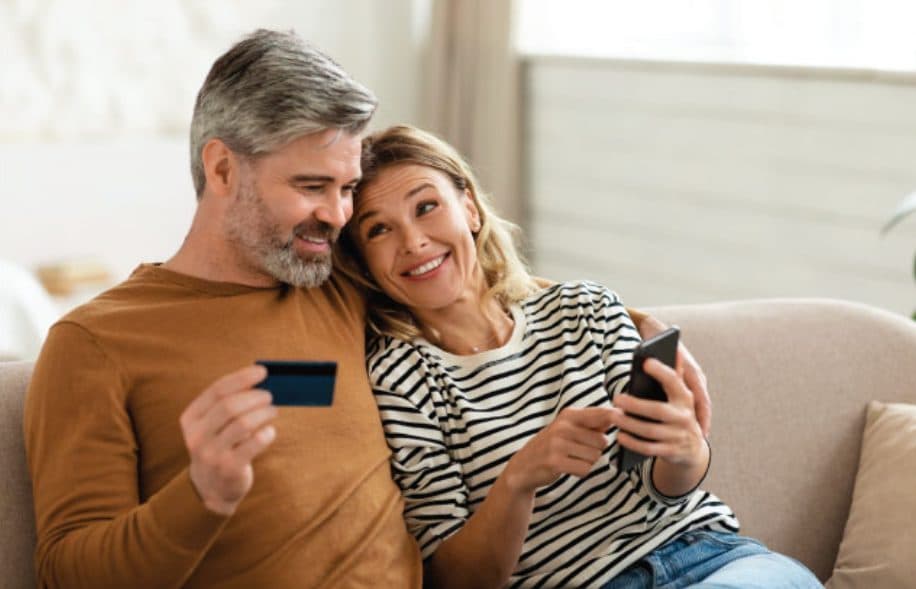 Couple on the couch paying online with a card and phone