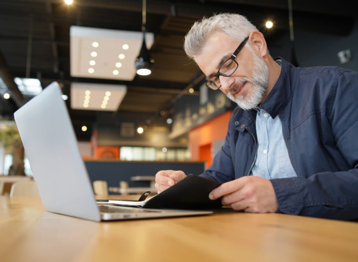 Man reading notes at his laptop