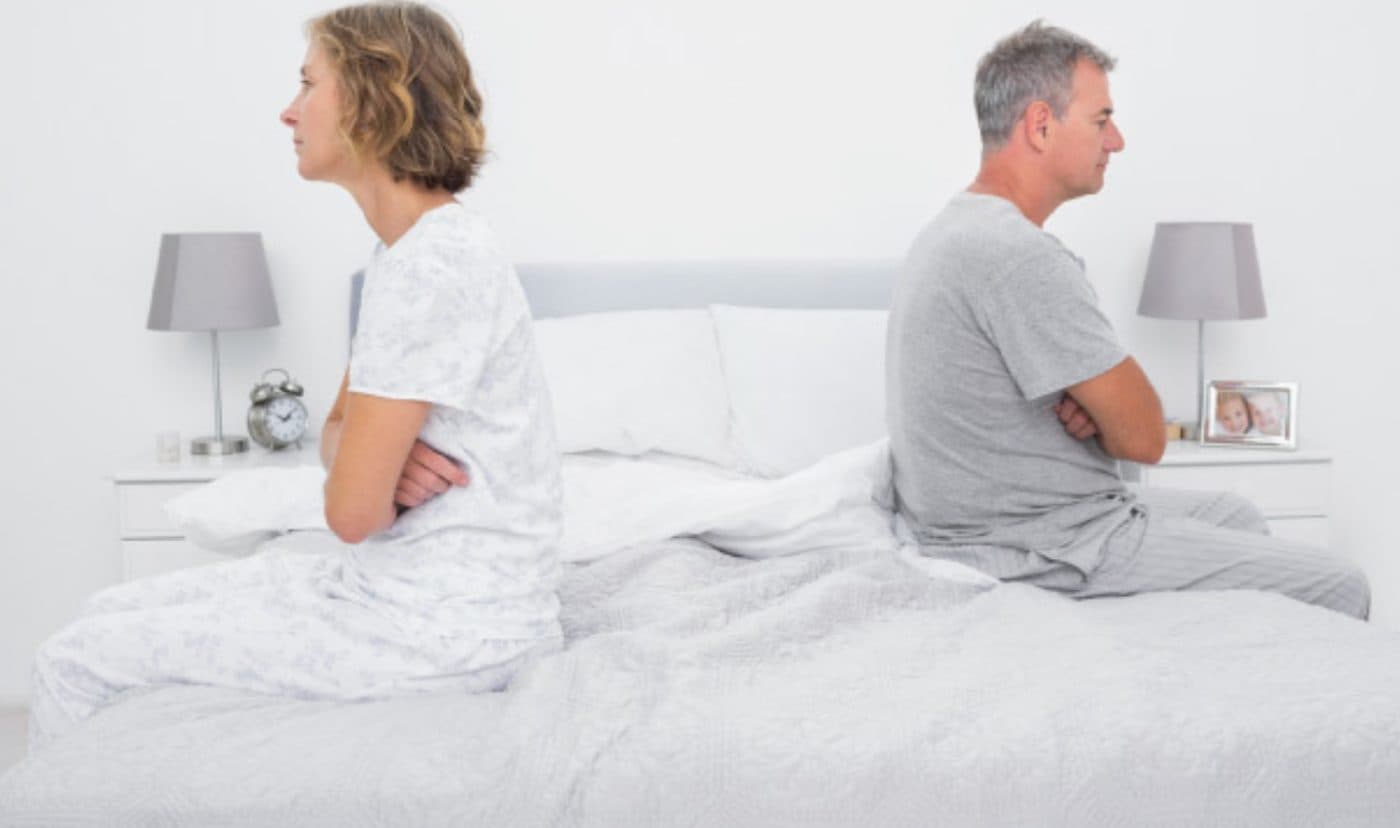 Couple sitting back to back on the bed after a poor night’s sleep